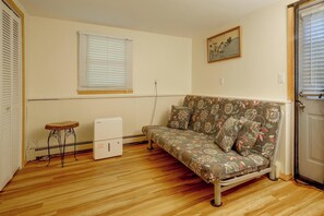 A small living room with a sofa, a radiator, a table, and a door. - Trailside Escape! Cozy Stormville Apartment (Stormville)