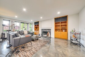 Ein modernes Wohnzimmer mit einer Couch, einem Kamin, Holzregalen und einem Couchtisch.