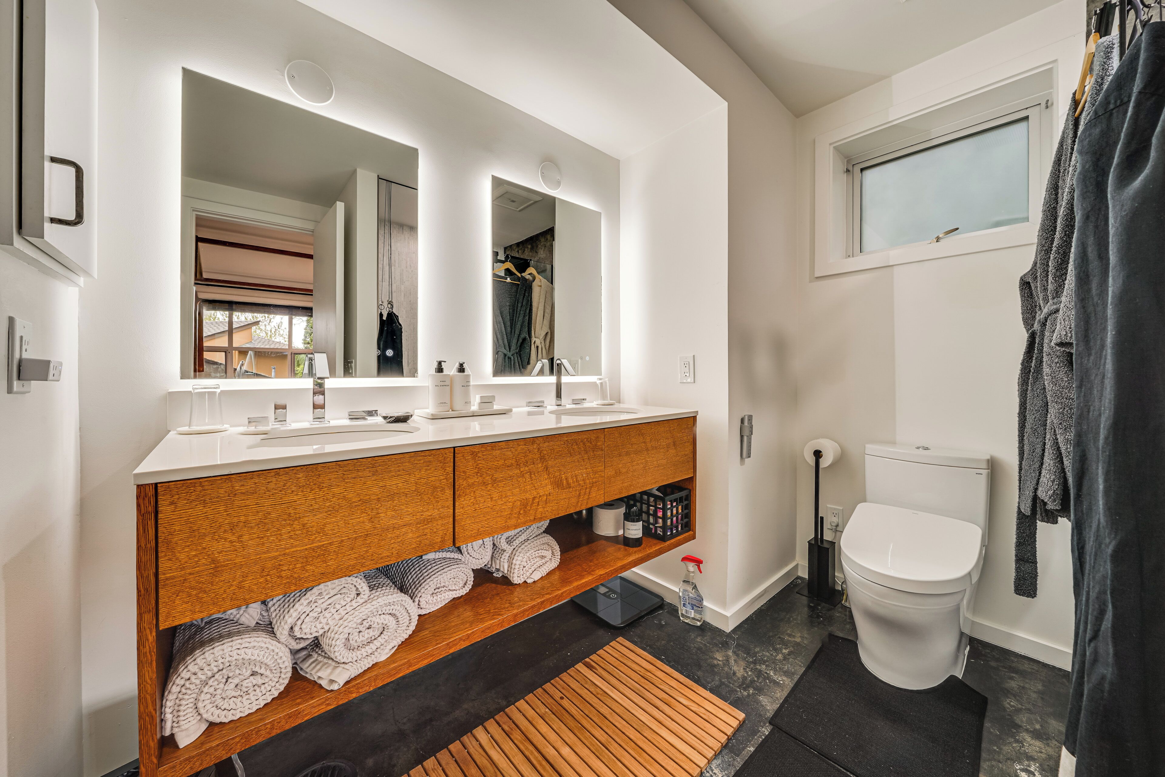 Ein modernes Badezimmer mit weißem Waschtisch, einem großen Spiegel, Toilette und einer Duschvorhang.