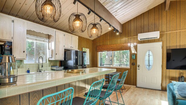 Una cocina con armarios de madera, un refrigerador de acero inoxidable, una isla grande con taburetes de bar e iluminación colgante.