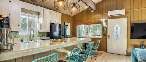 A kitchen with wooden cabinets, a stainless steel refrigerator, a large island with bar stools, and pendant lighting.