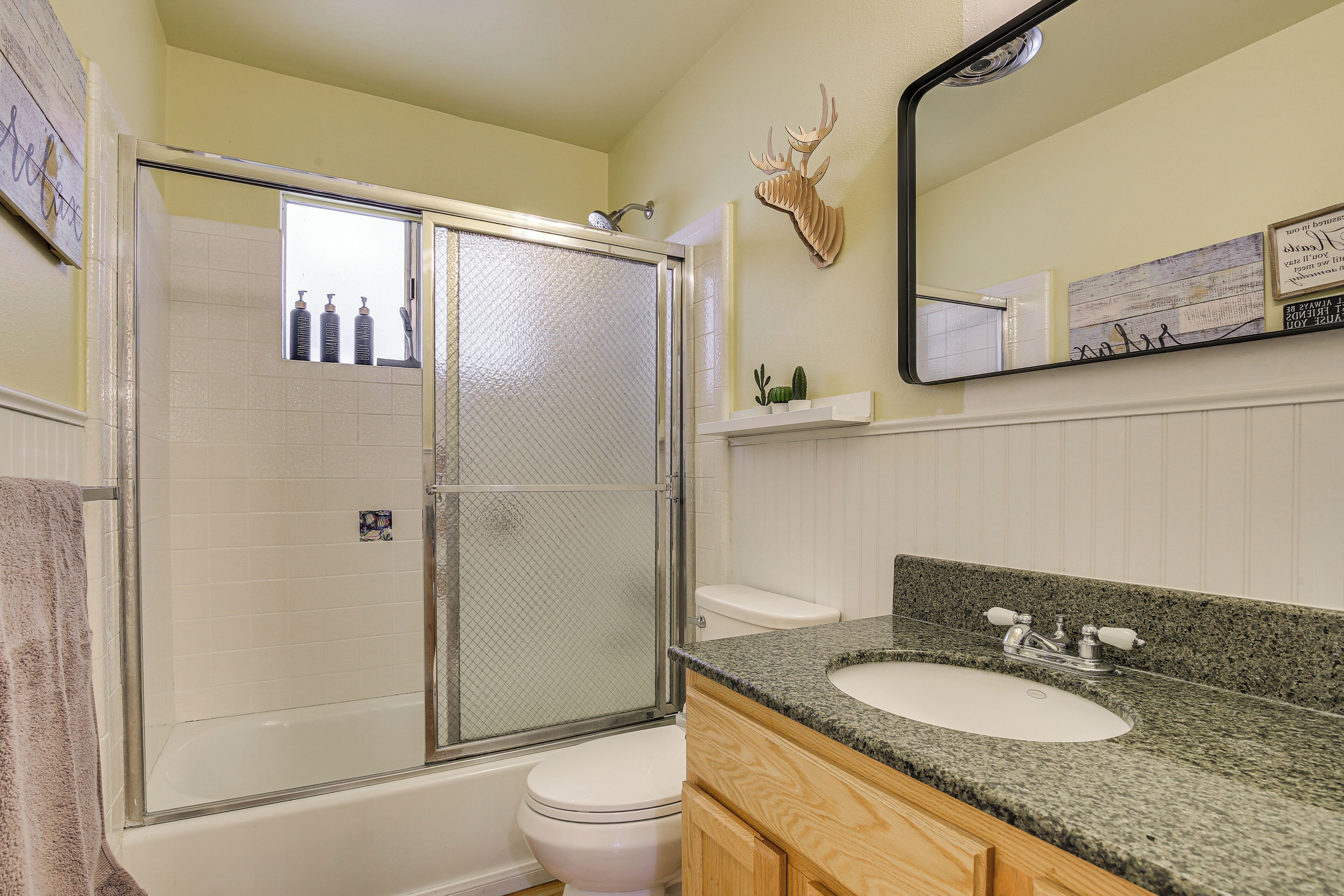 A bathroom with a shower enclosure, toilet, sink, and mirror.