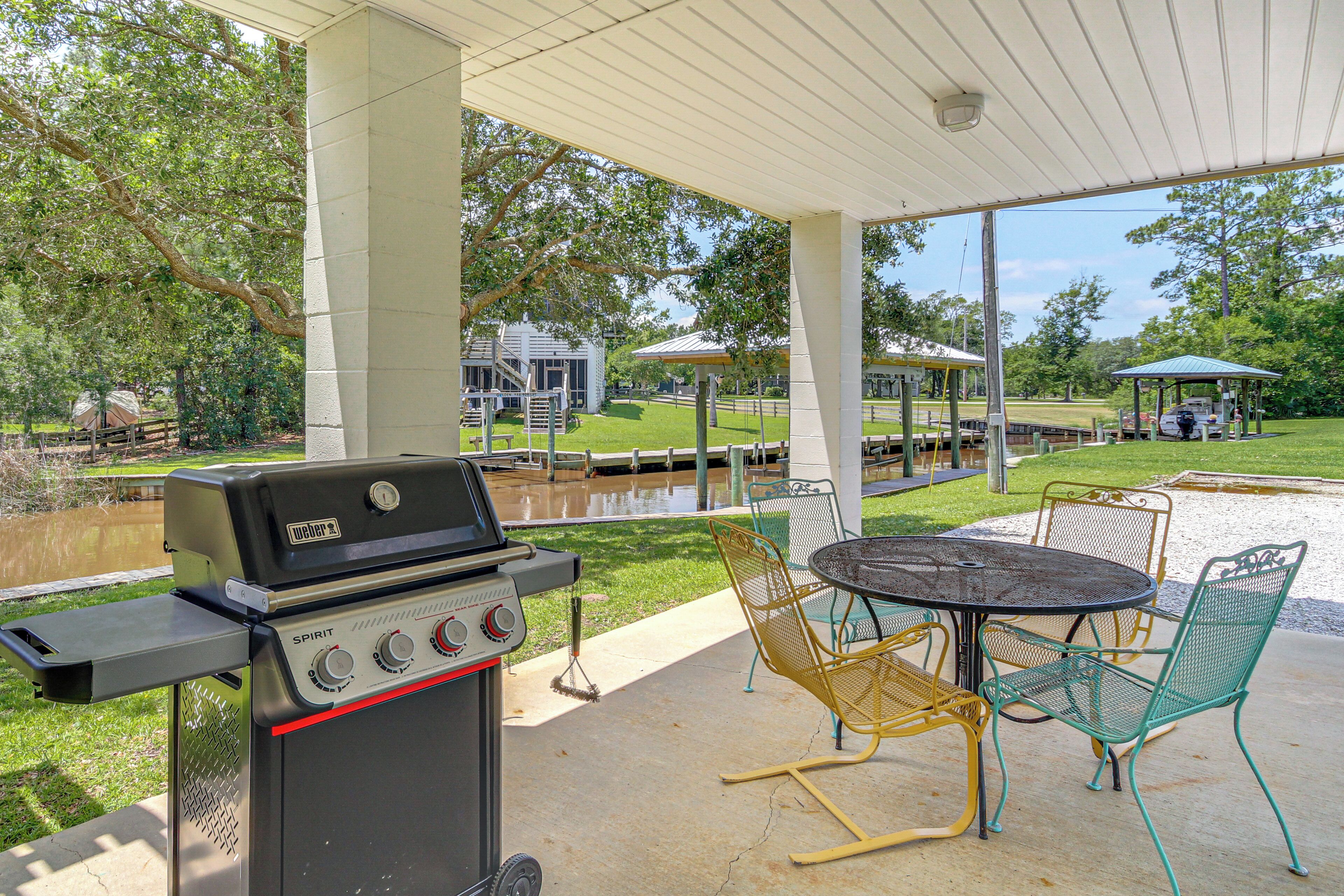Une terrasse extérieure avec un barbecue, des chaises et une vue sur un parc.