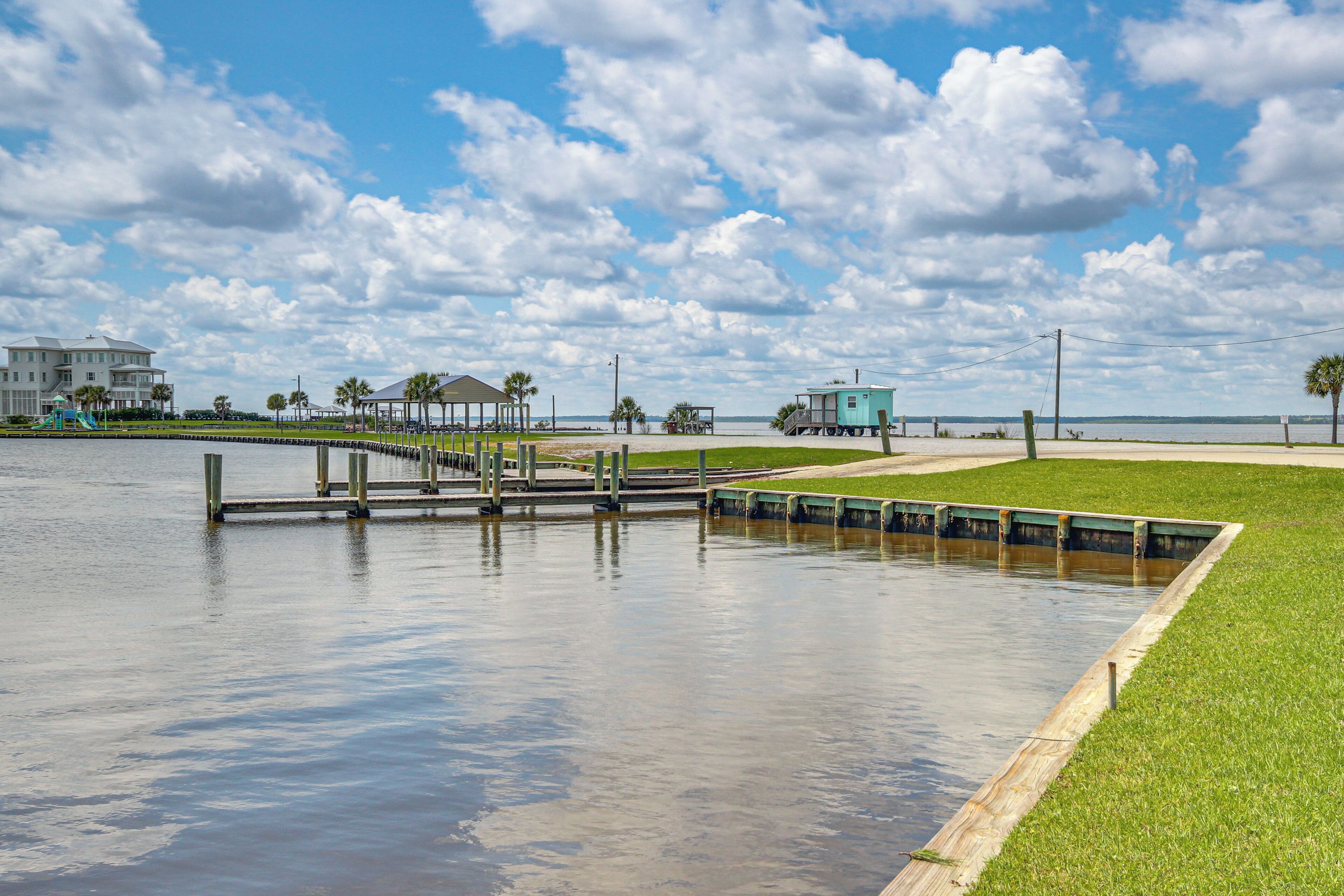 A waterfront park with a wooden dock, a small pavilion, and a grassy area.