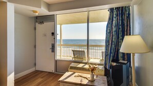 Ein Zimmer mit einer großen SchiebeglasTür, die auf einen Balkon mit Blick auf den Strand führt.