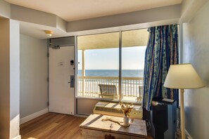 Ein Zimmer mit einer großen SchiebeglasTür, die auf einen Balkon mit Blick auf den Strand führt.