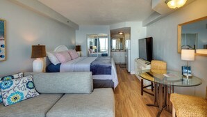 Ein Hotelzimmer mit Bett, Sofa, Glastisch, Fernseher und Spiegel.