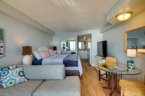 Ein Hotelzimmer mit Bett, Sofa, Glastisch, Fernseher und Spiegel.