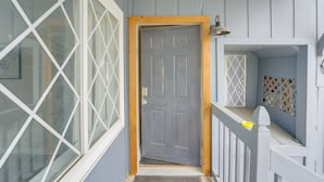 A wooden door with a white frame, a small porch with a white railing, and a window with a diamond pattern. - Creekside Picnic Area! Stay Near Blue Water Bridge (Port Huron)