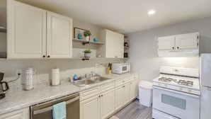 A kitchen with white cabinets, a stove, a microwave, and a sink. - Creekside Picnic Area! Stay Near Blue Water Bridge (Port Huron)