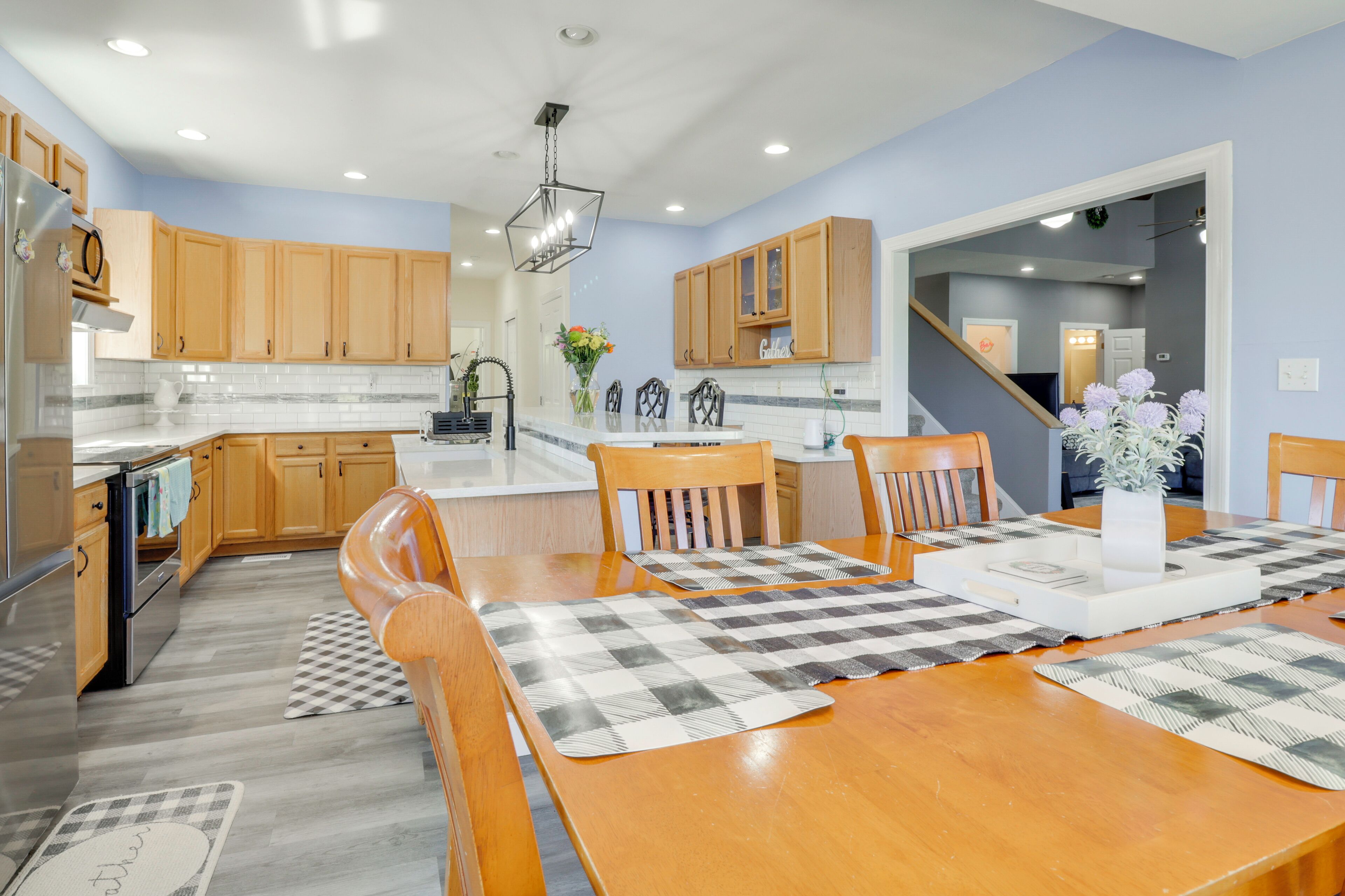A modern kitchen with wooden cabinets, a central island, and a dining area with a checkered placemat.