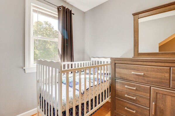 A room with a crib, a dresser, and a window with curtains.