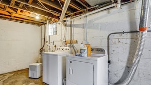 A laundry room with two washers and a dryer, exposed ductwork, and a water heater. - Gateway to Dtwn Port Huron & Lake! Cozy Home (Port Huron)