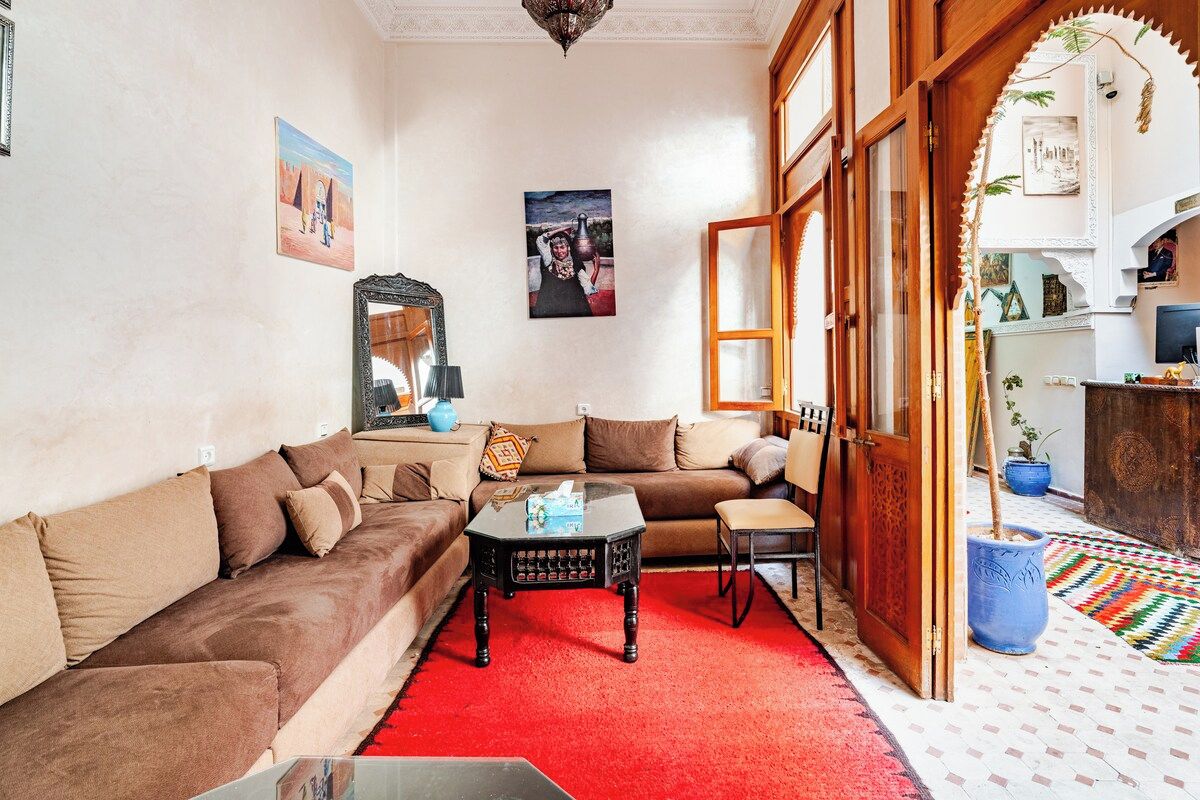A living room with a brown sofa, a black coffee table, and a red carpet.