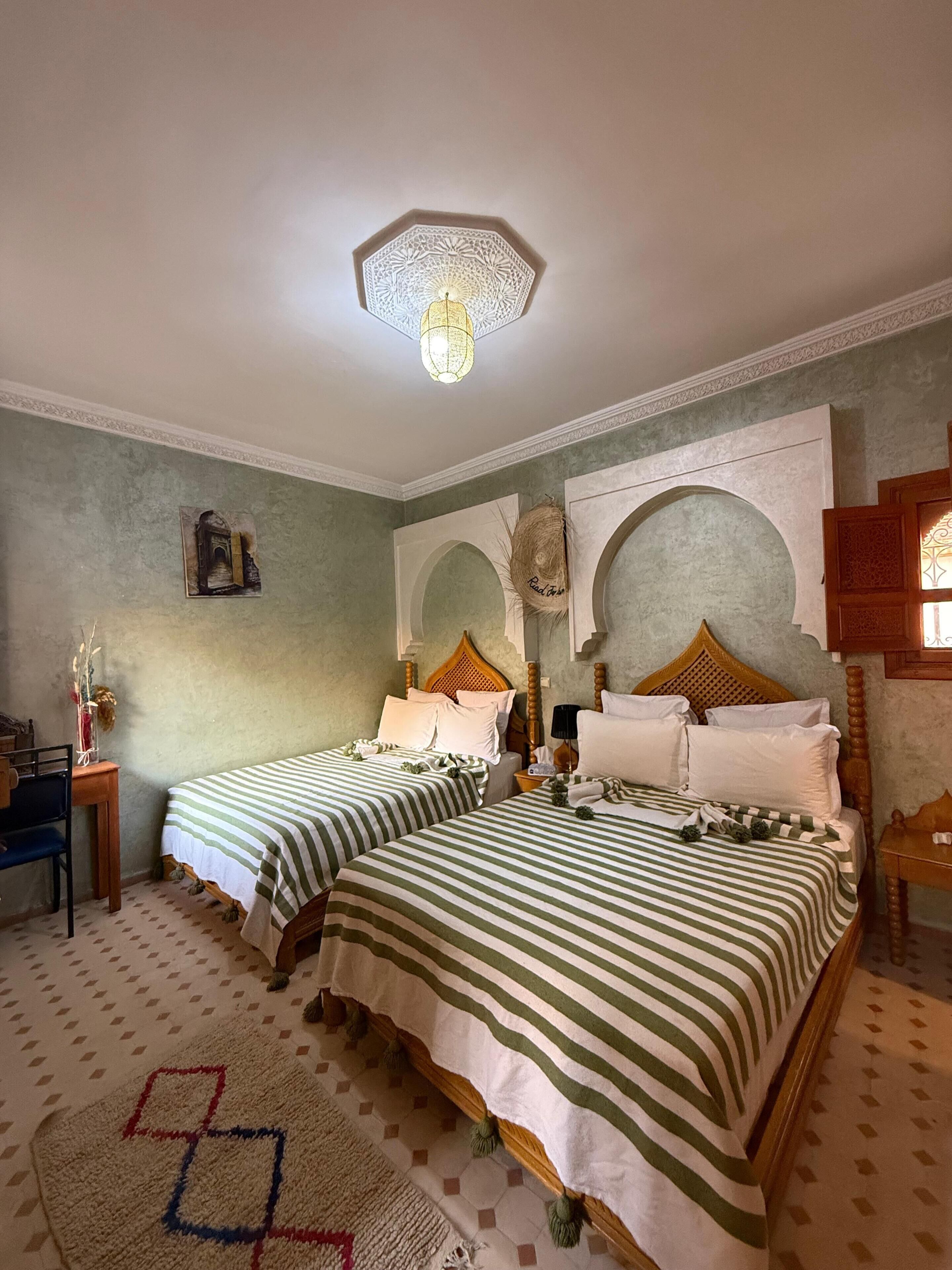 A room with two beds, a desk, and a decorative ceiling light.