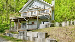 A two-story cabin with a balcony, a star decoration, and a white picket fence. - Mountain Views & Hot Tub - Your Blue Ridge Getaway (Barnardsville)