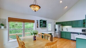 A kitchen with wooden dining table and chairs, green cabinets, and a hanging light fixture. - Mountain Views & Hot Tub - Your Blue Ridge Getaway (Barnardsville)