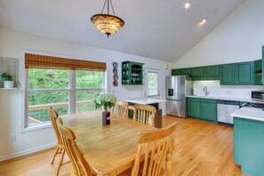 A kitchen with wooden dining table and chairs, green cabinets, and a hanging light fixture. - Mountain Views & Hot Tub - Your Blue Ridge Getaway (Barnardsville)