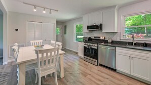 A modern kitchen with white cabinetry, a dining table, and chairs. - Dock & Pavilion! Lake Norman Retreat on Quiet Cove (Mooresville)