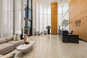 Eine moderne Hotelhalle mit Empfangsbereich, Sitzgelegenheiten und großen Fenstern.