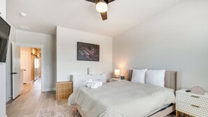 Ein modernes Schlafzimmer mit einem großen Bett, Nachttischen, einem Deckenventilator und einem Gemälde an der Wand.