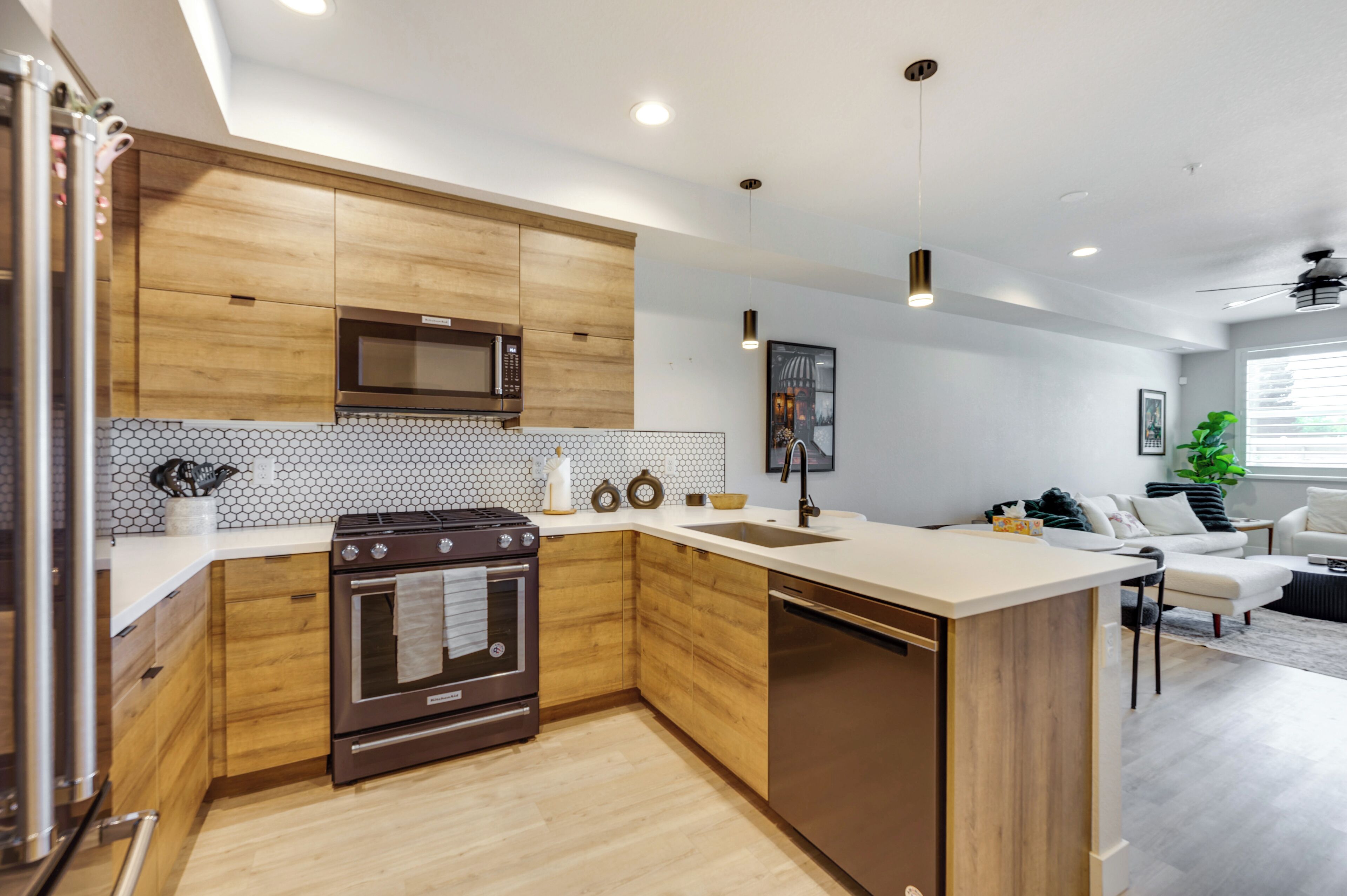 Una cocina moderna con armarios de madera, microondas, horno y lavavajillas.
