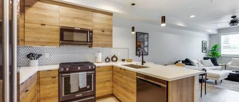 Una cocina moderna con armarios de madera, microondas, horno y lavavajillas.