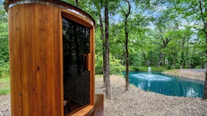 Uma cabana de madeira com porta de vidro, rodeada por uma floresta e um lago.