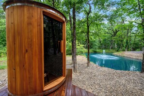 Eine Holzhütte mit Glastür, umgeben von Wald und Teich.