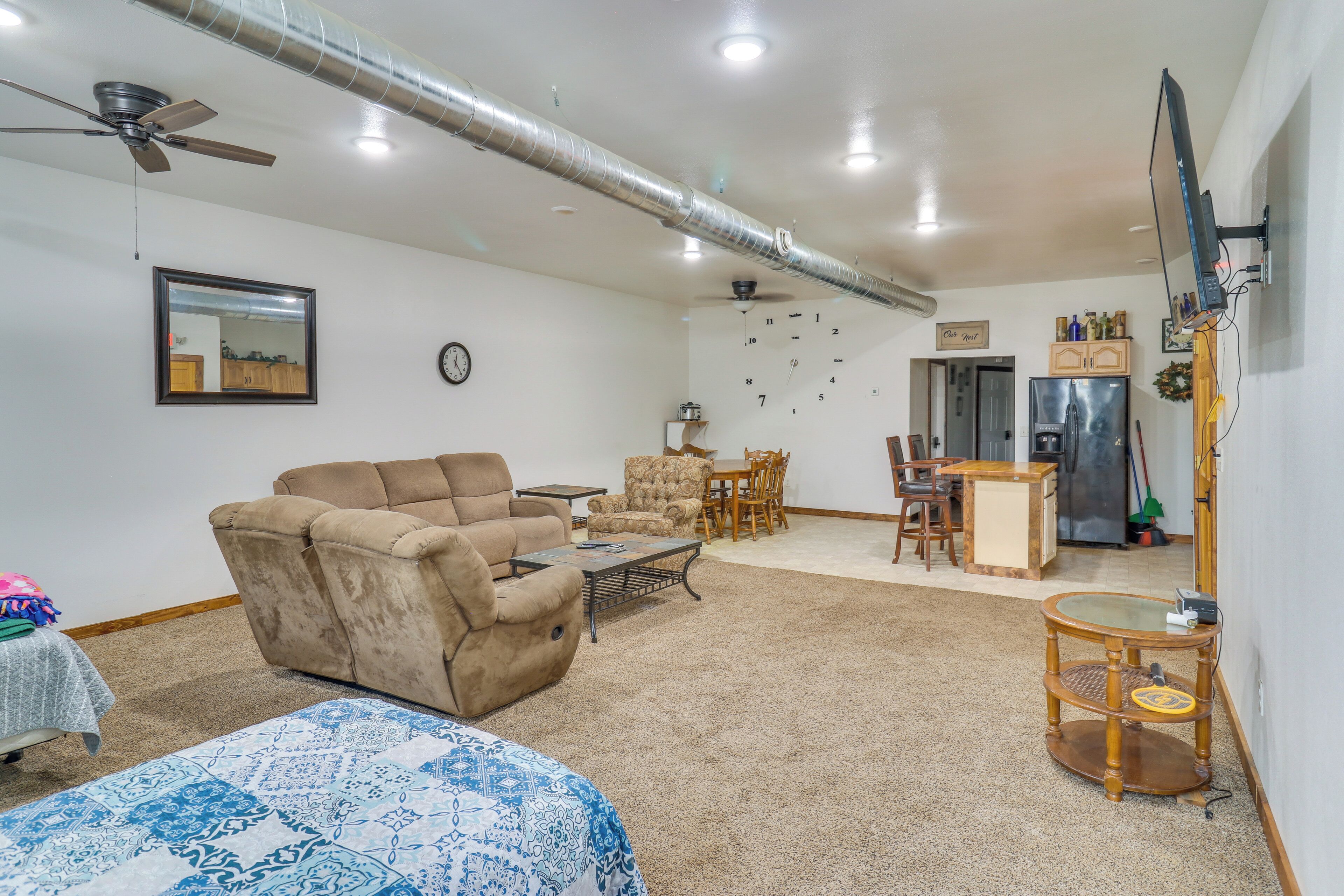 A living room with a sofa, armchair, coffee table, and a TV mounted on the wall.