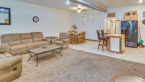 Un salon comprenant un canapé, une table basse, une table à manger, des chaises et un coin cuisine avec un réfrigérateur.