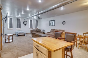 Un salón amplio con una mesa de comedor de madera, dos sofás, una mesa baja y un televisor montado en la pared.