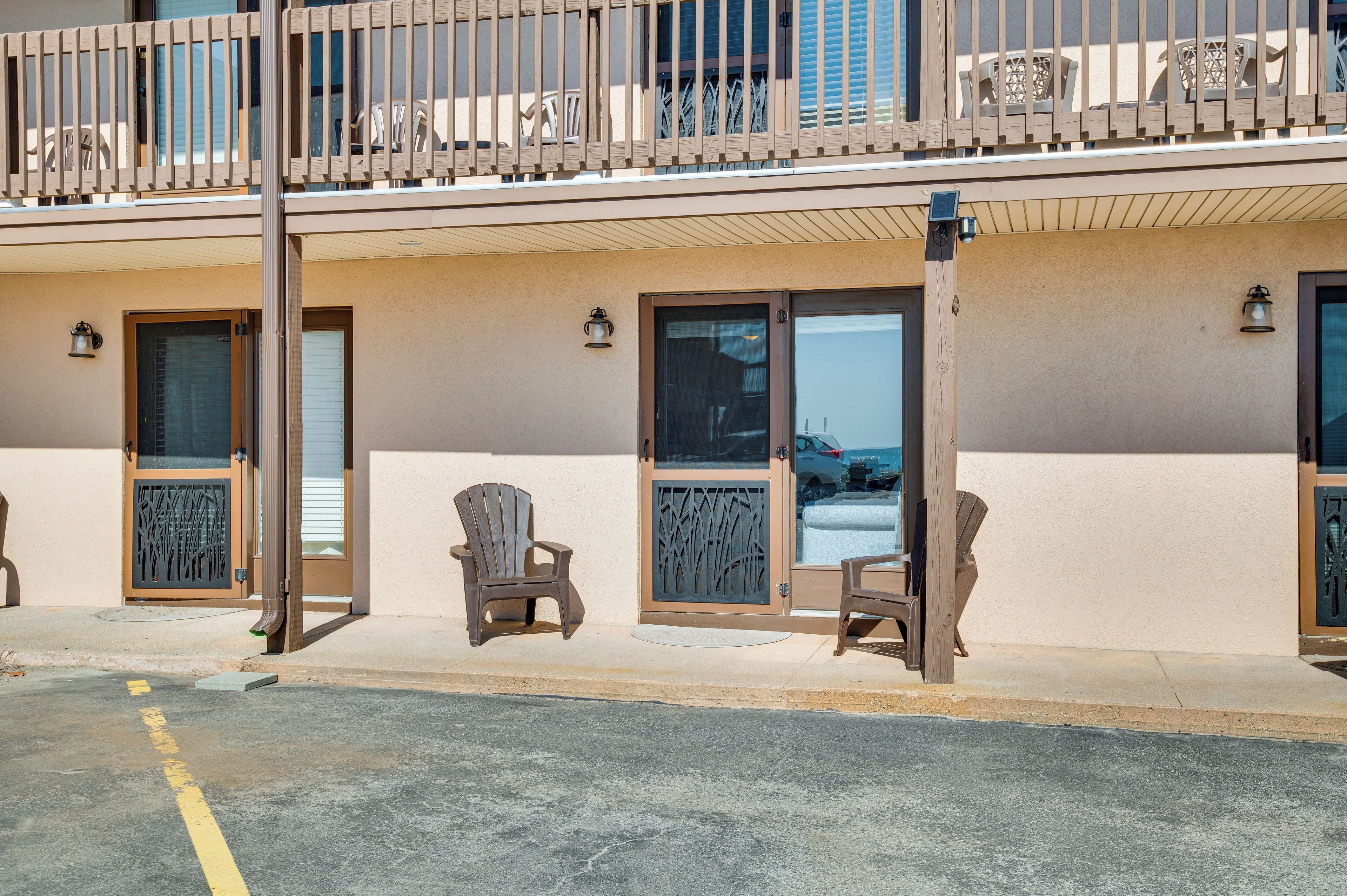 Un hotel con un balcone, due sedie di legno e una porta con cancello in metallo.