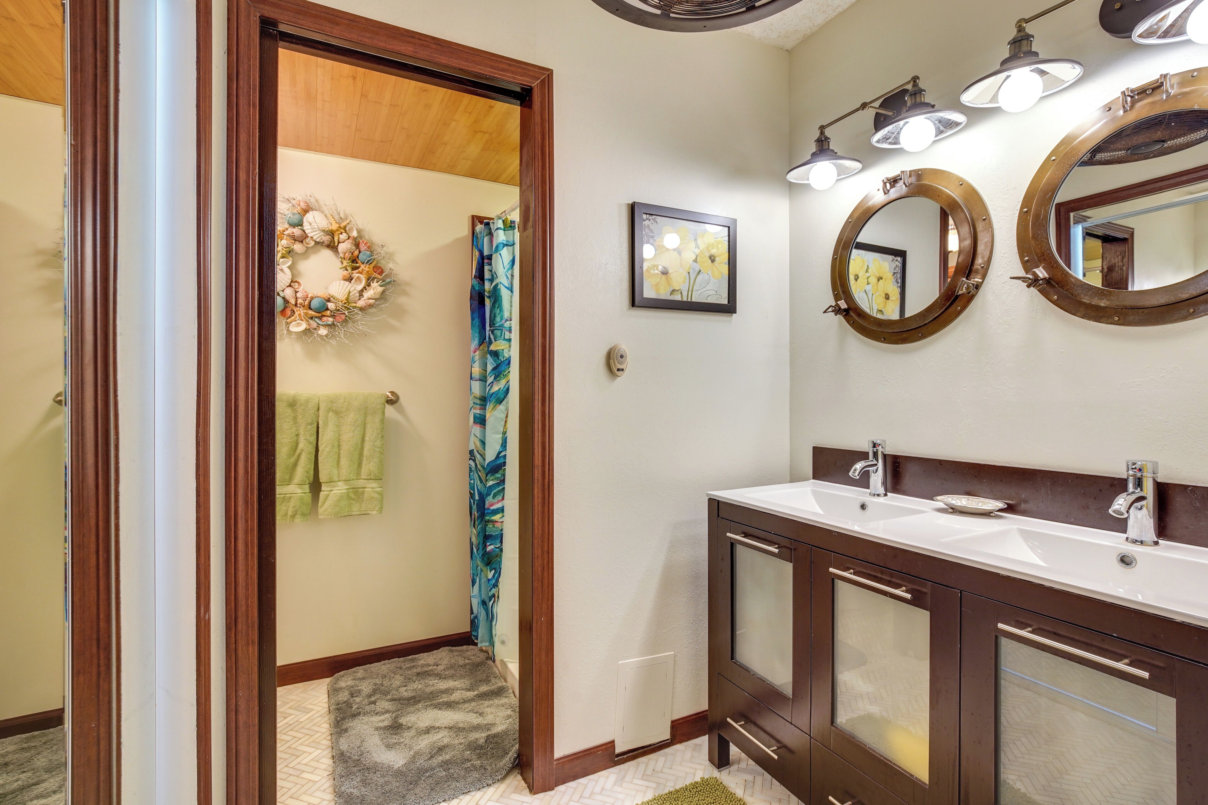 A bathroom with a double vanity, a shower curtain, a towel rack, and a mirror with a decorative frame.