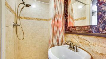 A bathroom with a shower, sink, and mirror.