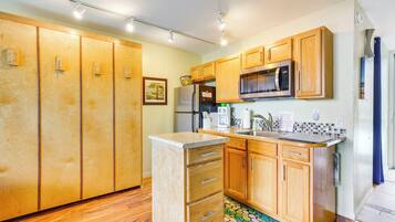 A kitchen with wooden cabinets, a refrigerator, a microwave, and a sink.