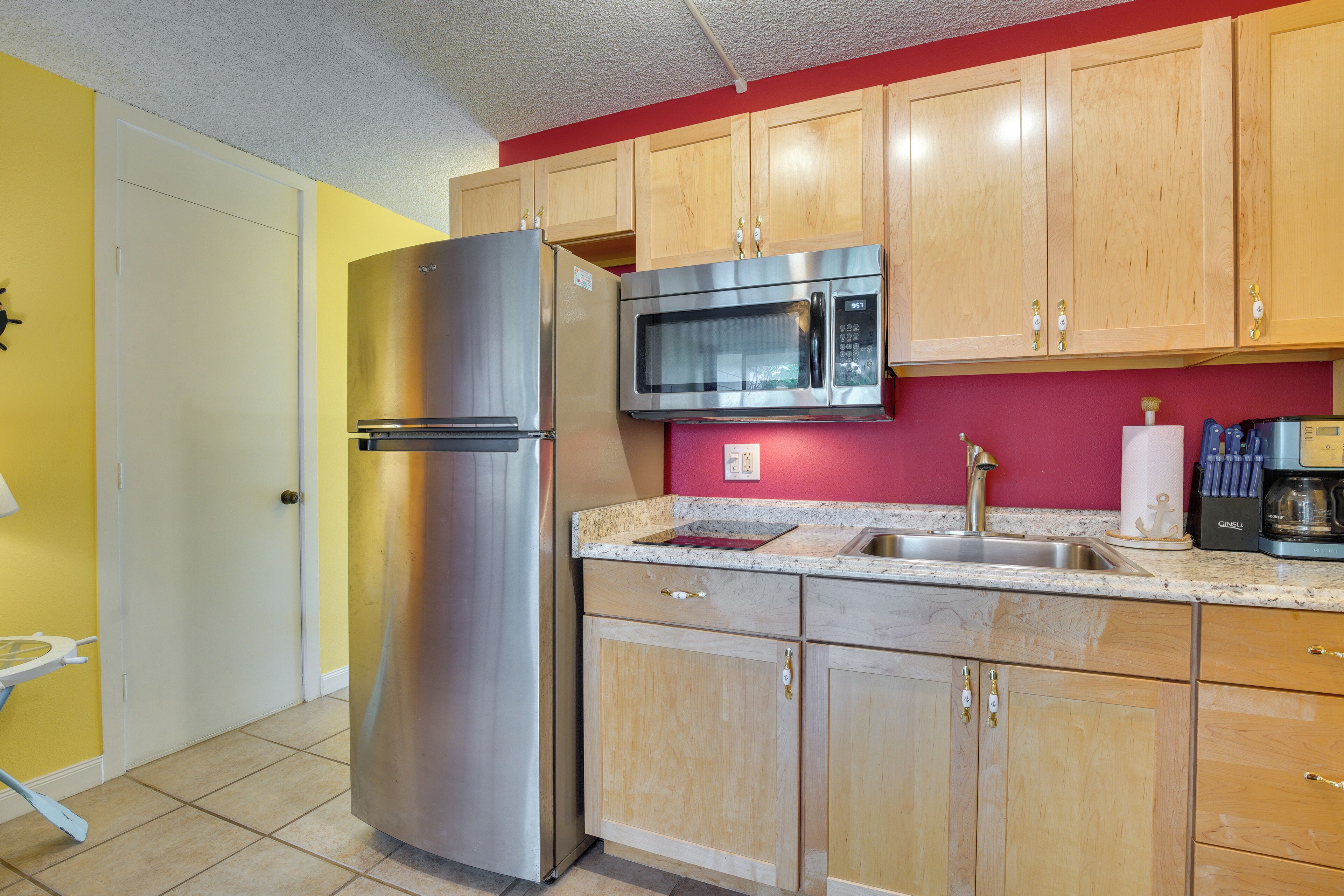 Een keuken met houten kastjes, een roestvrijstalen koelkast, een magnetron en een spoelbak.
