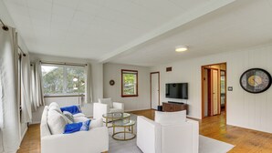 A spacious living room with a white sofa, a coffee table, and a television. - Lakefront Bliss in Mahopac! Charming Home w/ Dock (Mahopac)
