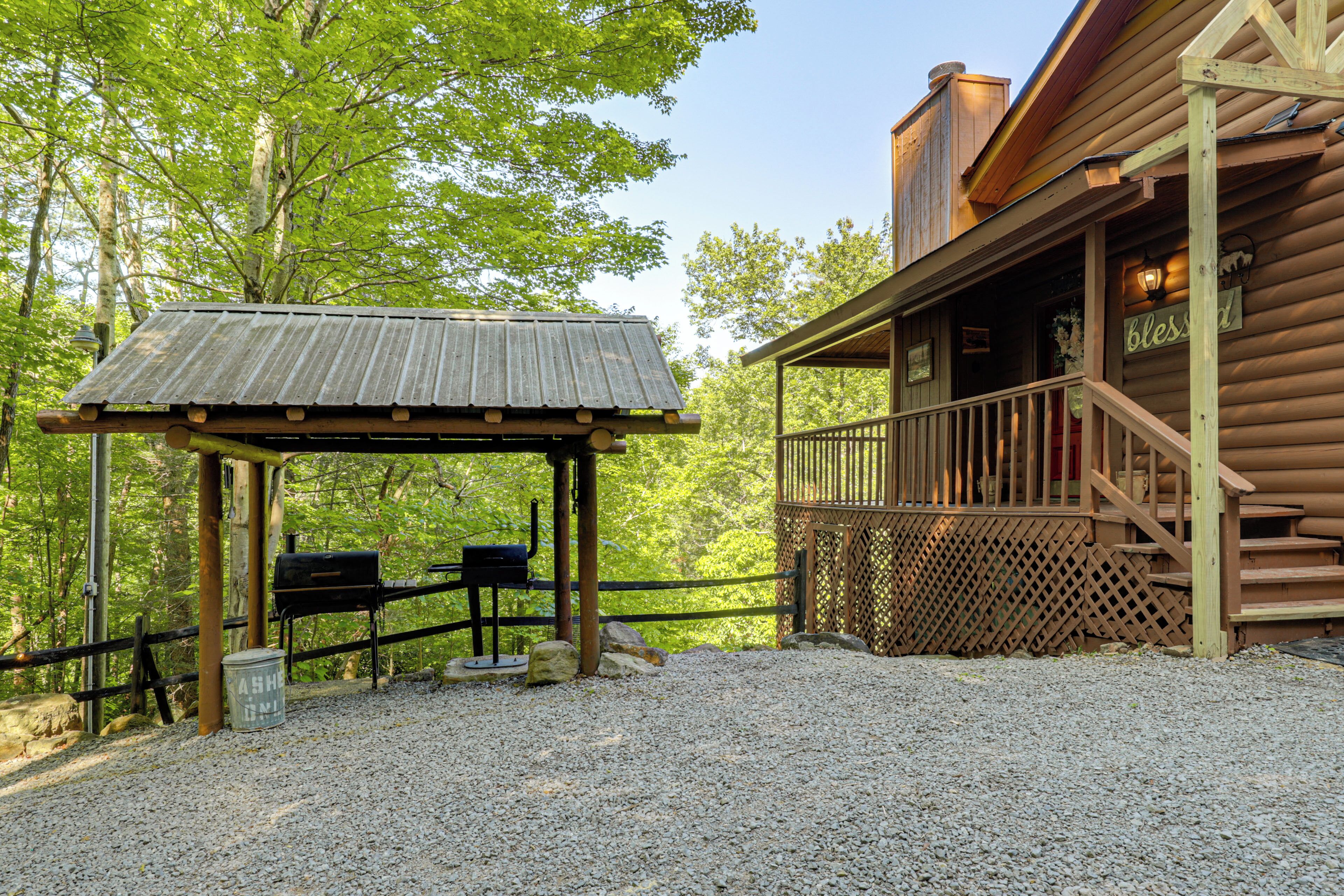A rustic cabin with a covered outdoor seating area, a wooden deck, and a gravel ground.