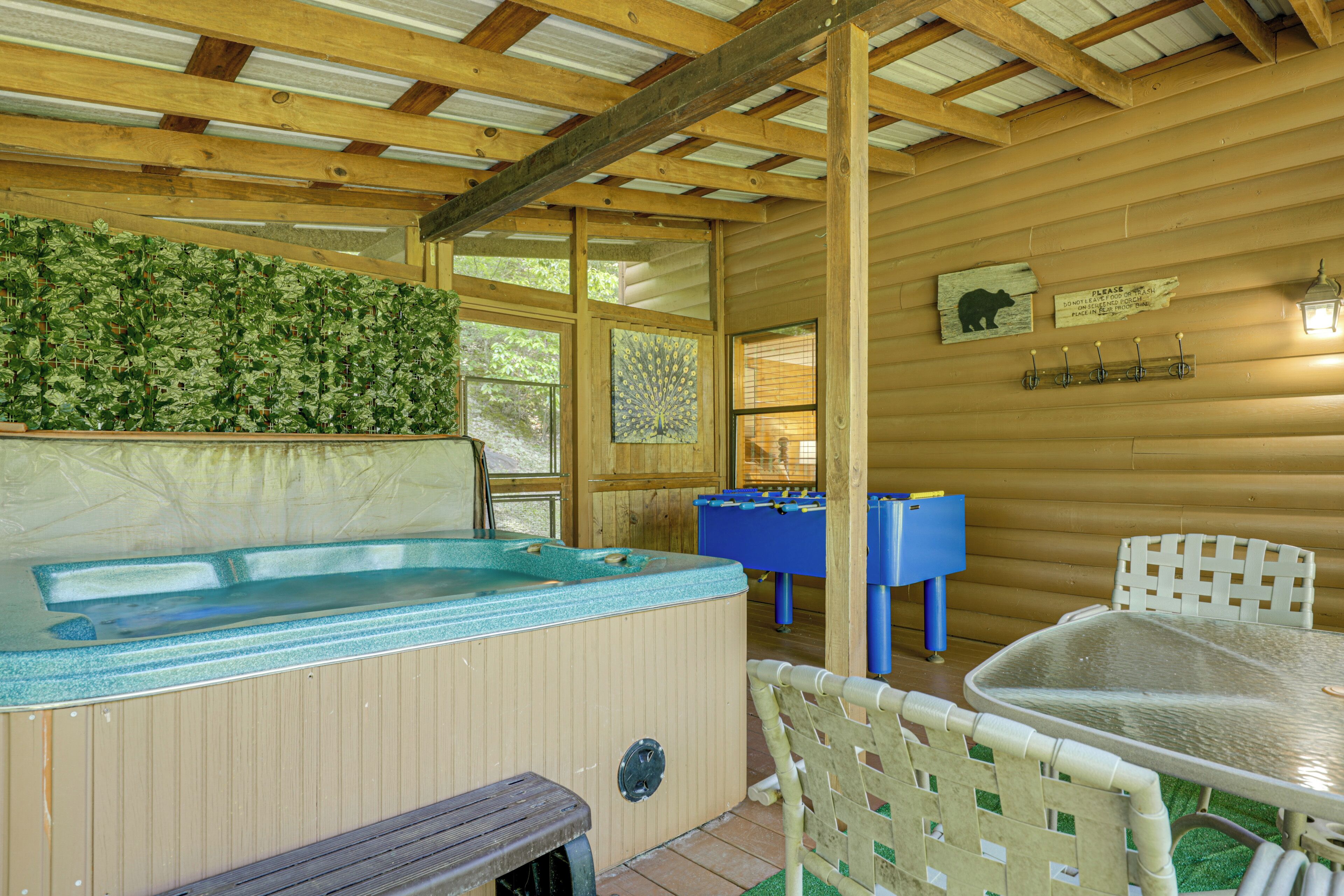 A wooden cabin with a hot tub, a foosball table, and a table with chairs.