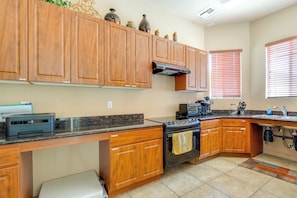 A kitchen with wooden cabinets, a stove, a microwave, and a countertop with a printer.