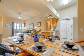 A dining area with a wooden table set for four, a vase with flowers, and a kitchen in the background. - 2 Resort-style Pools! Condo Near Mesa Market Place (Mesa)