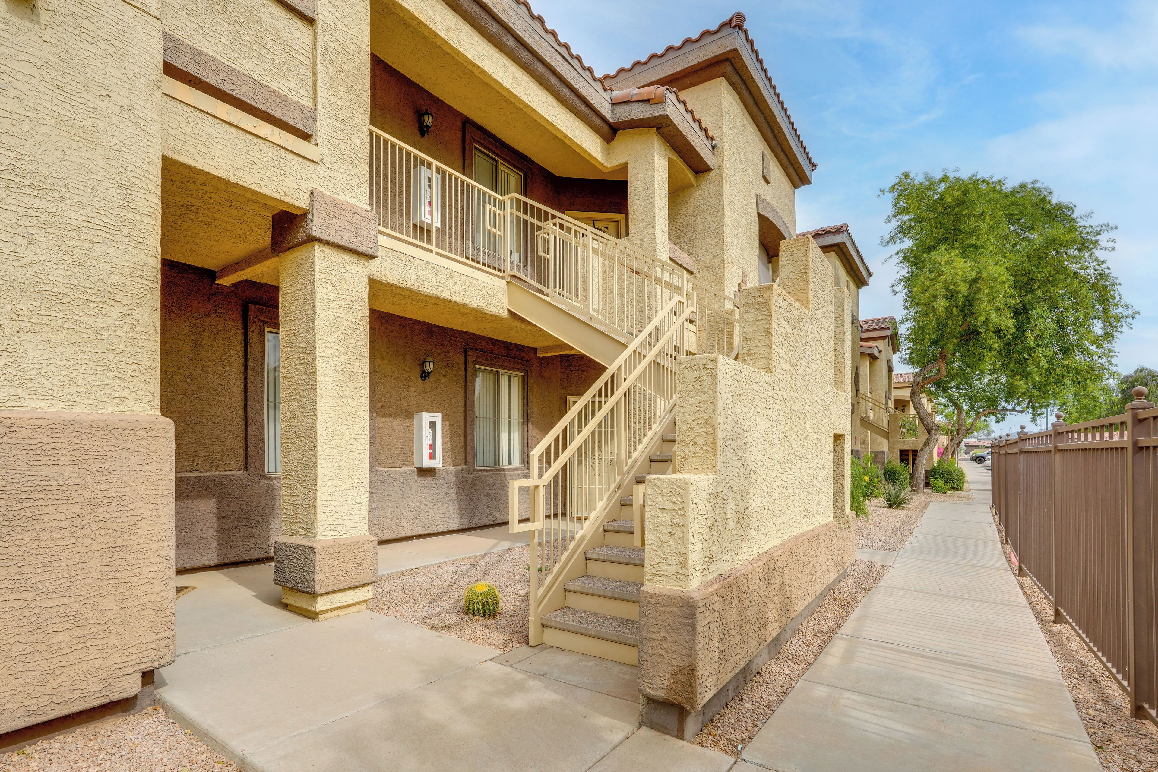 A multi-story building with a balcony, a staircase, and a gated driveway.