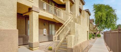 A multi-story building with a balcony, a staircase, and a gated driveway.