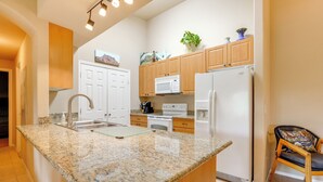A kitchen with granite countertops, white appliances, wooden cabinets, and a chair. - 2 Resort-style Pools! Condo Near Mesa Market Place (Mesa)