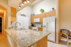 A kitchen with granite countertops, white appliances, wooden cabinets, and a chair. - 2 Resort-style Pools! Condo Near Mesa Market Place (Mesa)