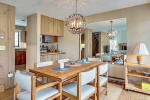 A spacious dining area with a wooden table and chairs, a chandelier, and a view into the kitchen. - Hike, Explore & Unwind: All-season Lincoln Retreat (Lincoln)