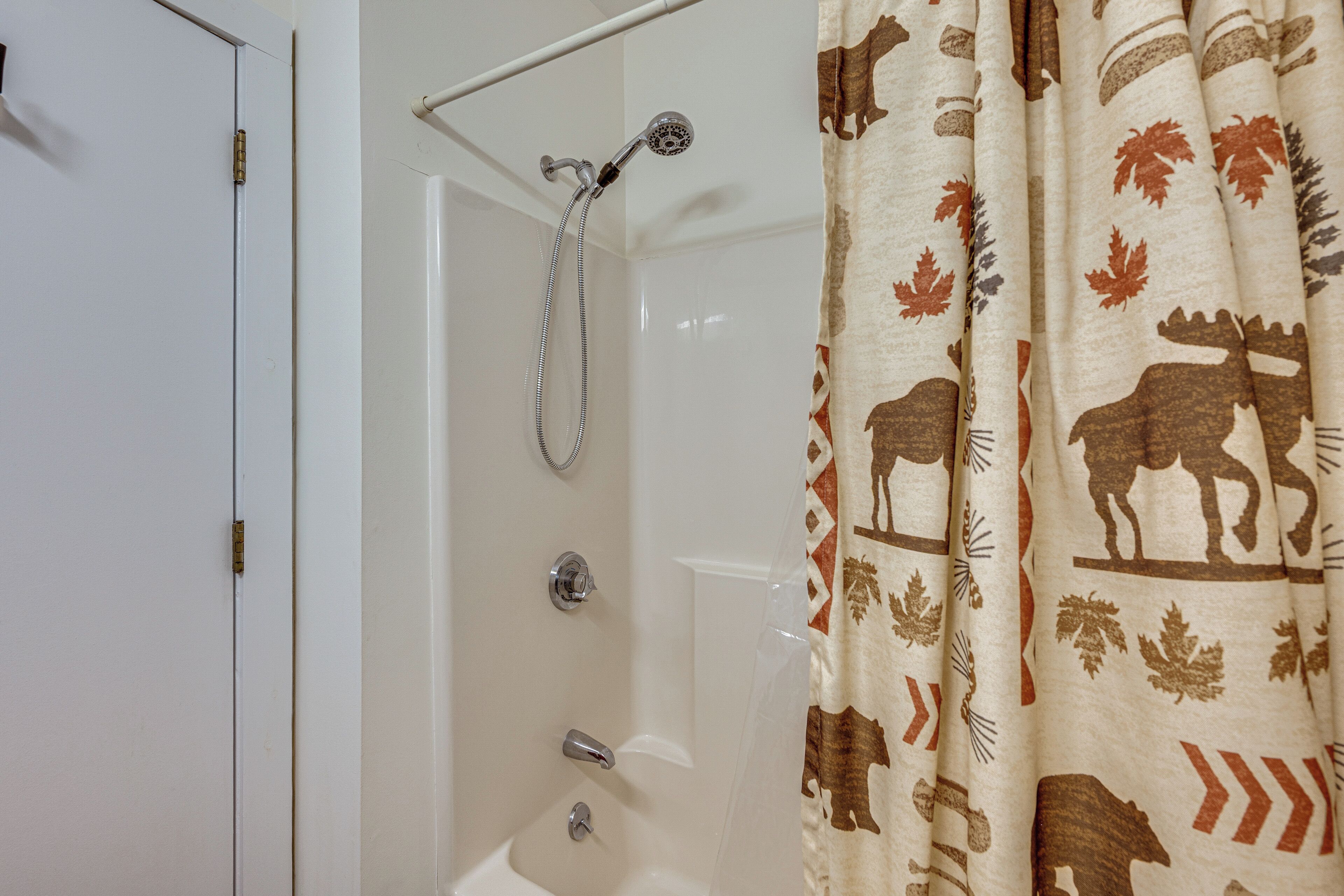 A bathroom with a shower, a bathtub, and a curtain with animal prints.