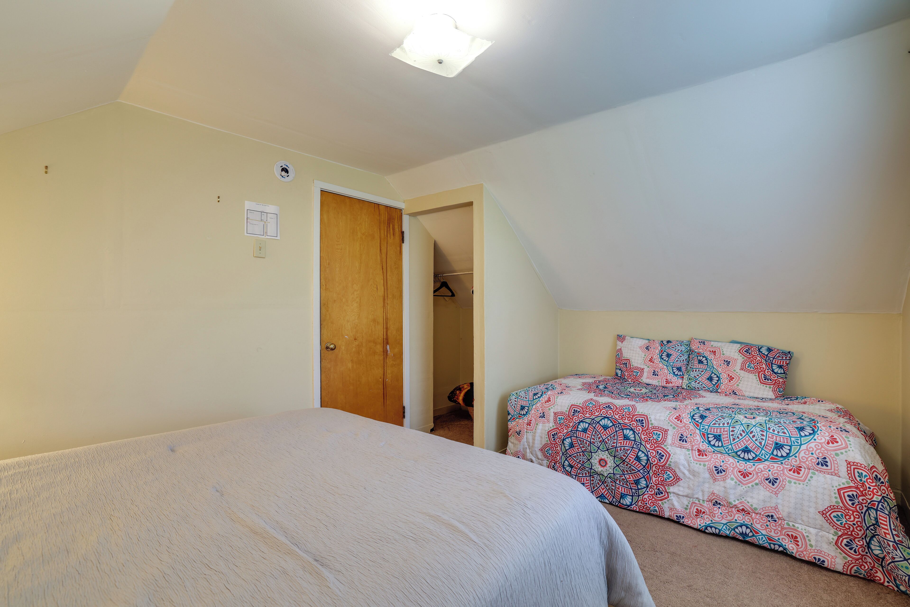 Una camera da letto con due letti, un armadio e una porta che dà su un'altra stanza.