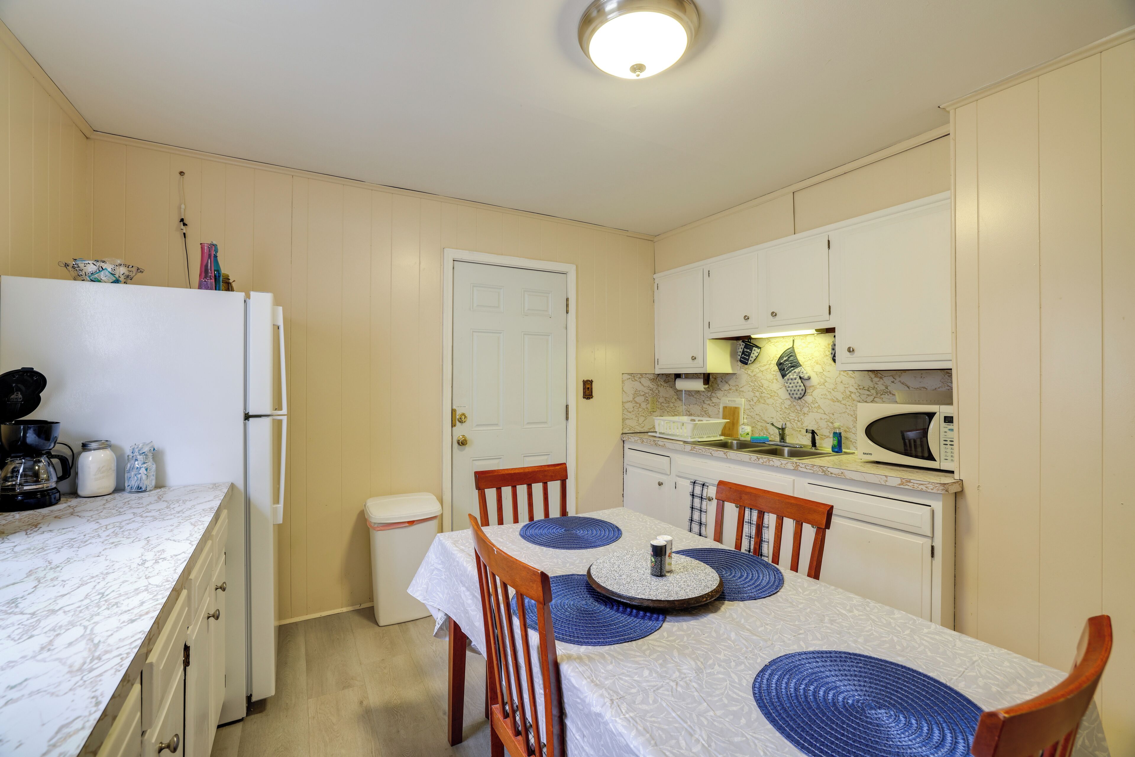 A compact kitchen with a refrigerator, microwave, and a dining table with chairs.